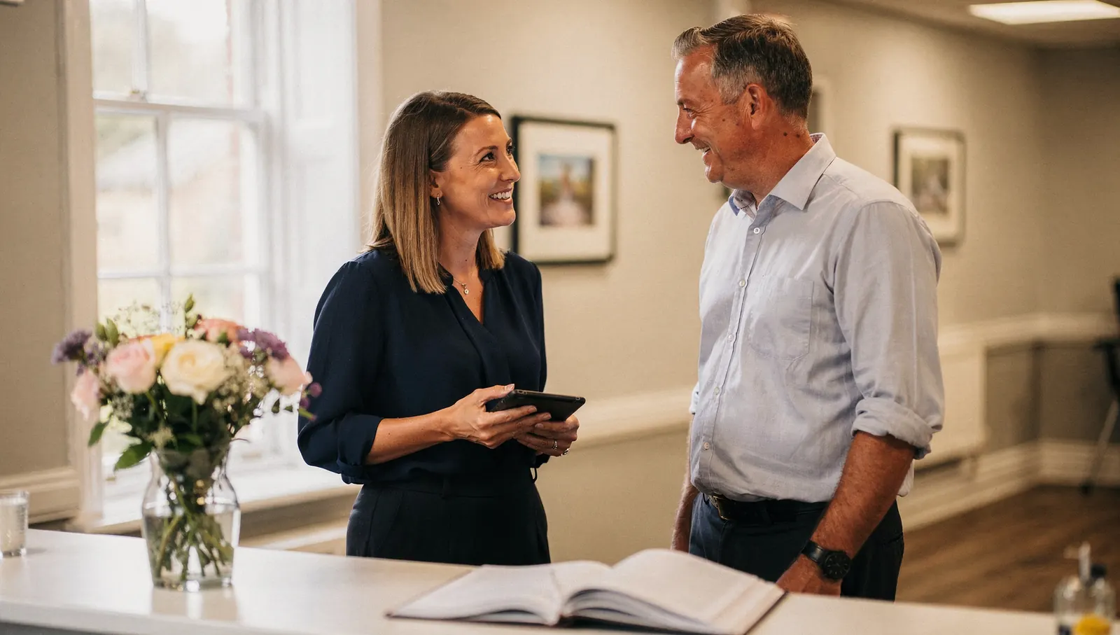 A regional director with a tablet talking with a home manager in a care home reception