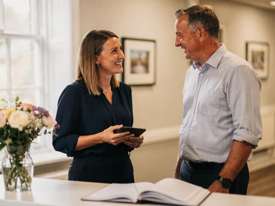 A regional director with a tablet talking with a home manager in a care home reception